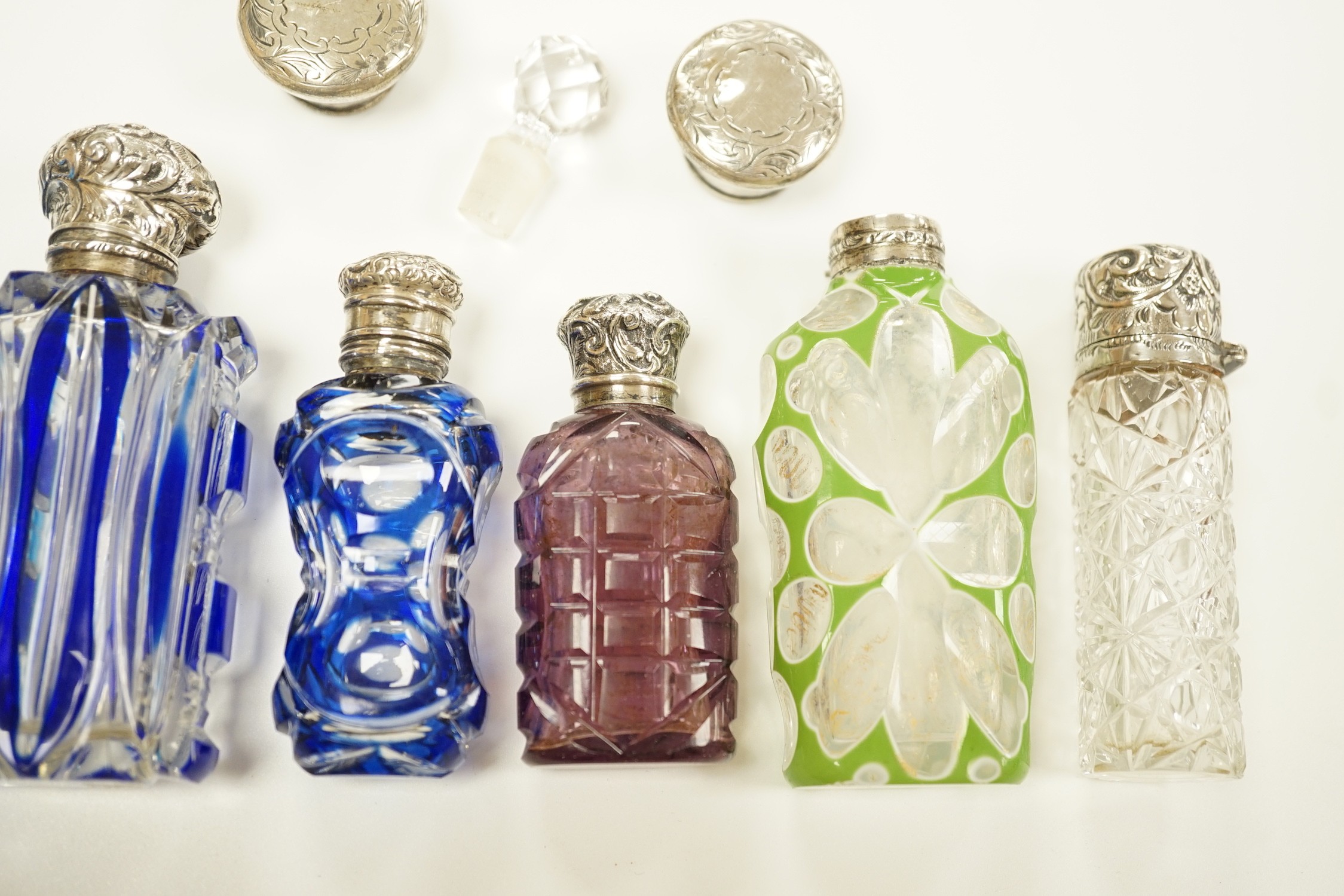 A late Victorian silver mounted cut glass scent bottle, Charles Boyton II, London, 1896, 82mm and six other late 19th/early 20th century, silver or white metal mounted coloured cut glass scent bottles (some a.f.) and two